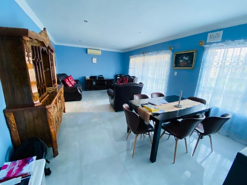 Spacious open-plan living and dining area featuring polished tiled flooring, recessed lighting, and an installed air conditioning unit.