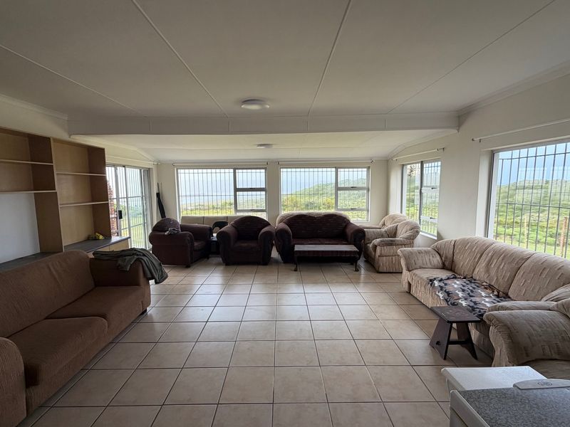 Spacious living area featuring tiled flooring, built-in shelving, and large windows with security bars offering scenic views.