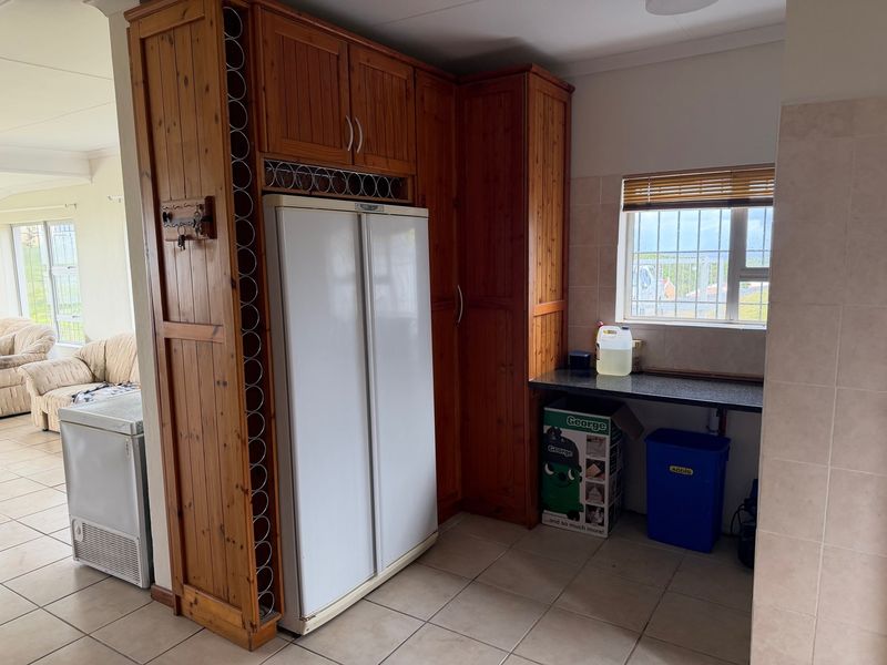 A functional scullery area featuring built-in timber cabinetry, integrated wine storage, and tiled flooring, providing additional prep and storage space.