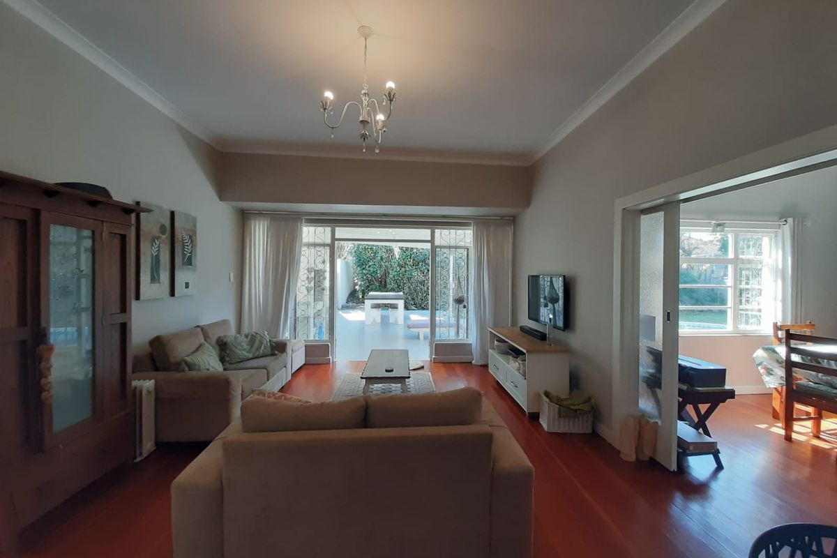 Spacious living room featuring warm hardwood flooring, elegant cove molding, and large sliding glass doors that provide seamless access to the outdoor patio area.