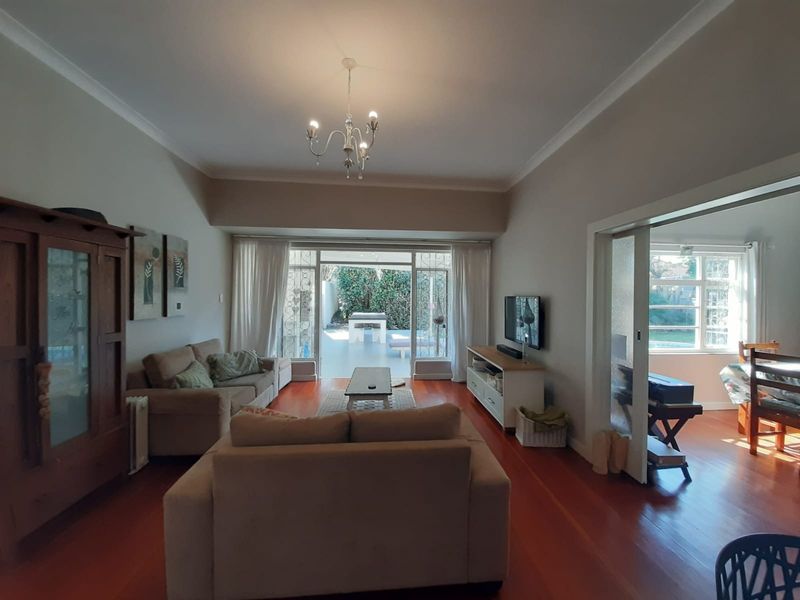 Spacious living room featuring warm hardwood flooring, elegant cove molding, and large sliding glass doors that provide seamless access to the outdoor patio area.