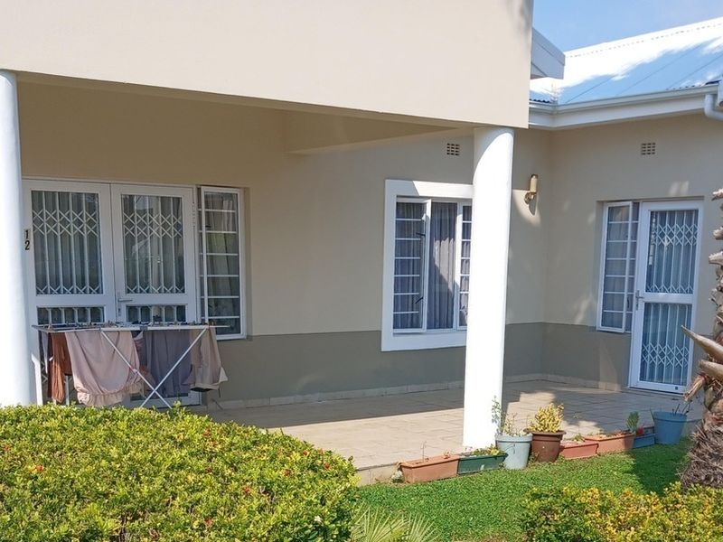 A covered patio area featuring tiled flooring, structural columns, and secure access points to the interior of the townhouse.