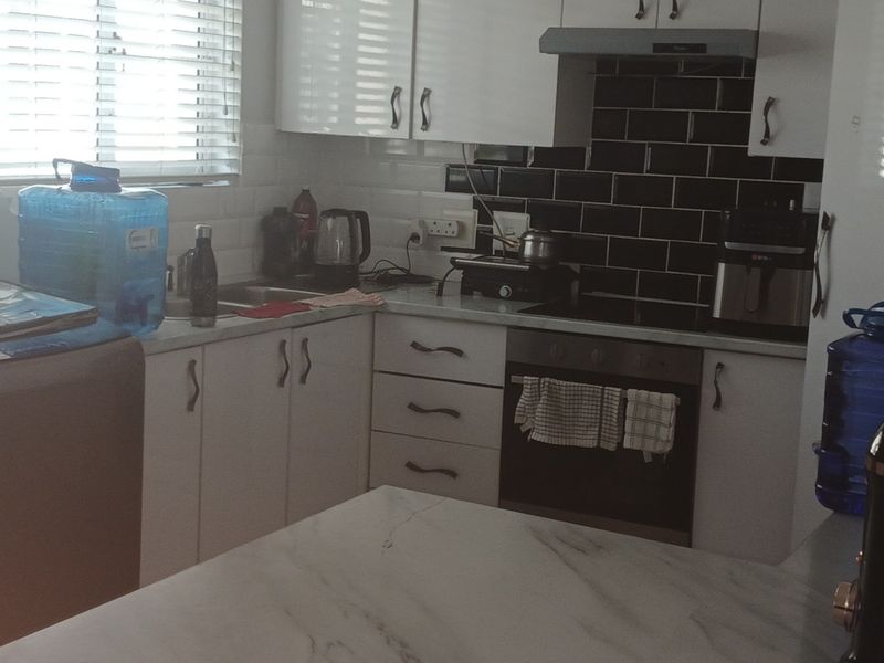 A functional kitchen featuring white cabinetry, a contrasting black subway tile backsplash, built-in oven, cooktop, and marble-look countertops.