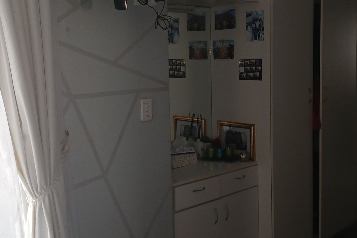 A bedroom featuring built-in cupboards and a vanity area with a mirror, offering functional storage space within the room.