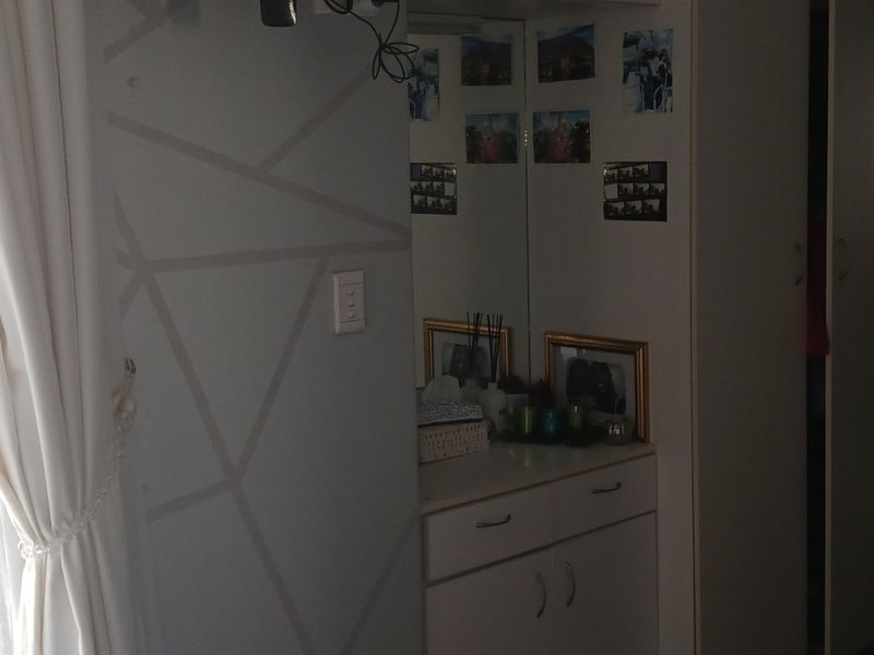 A bedroom featuring built-in cupboards and a vanity area with a mirror, offering functional storage space within the room.