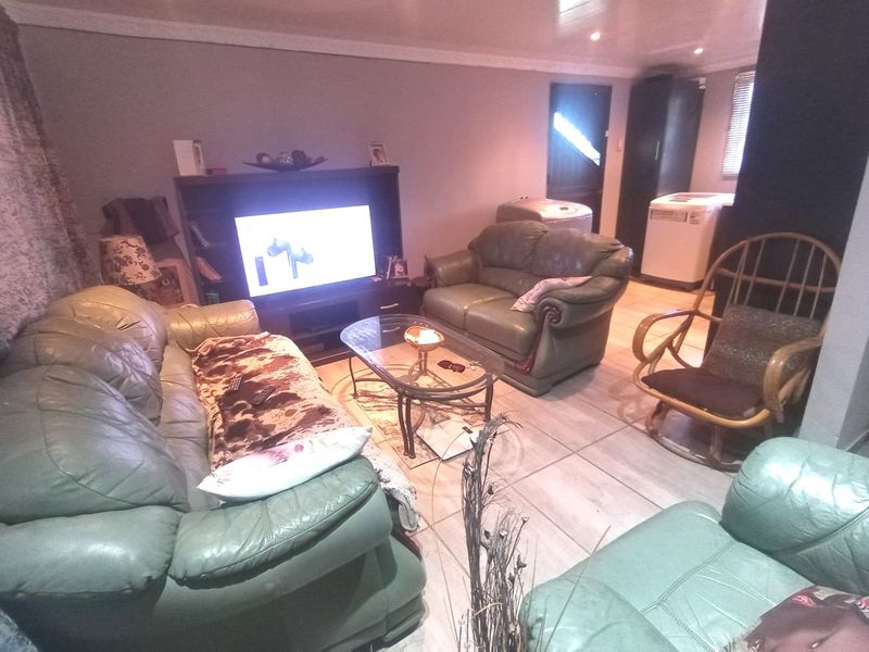A living room area featuring tiled flooring, recessed downlighting, and decorative cornicing, providing a functional space for relaxation.