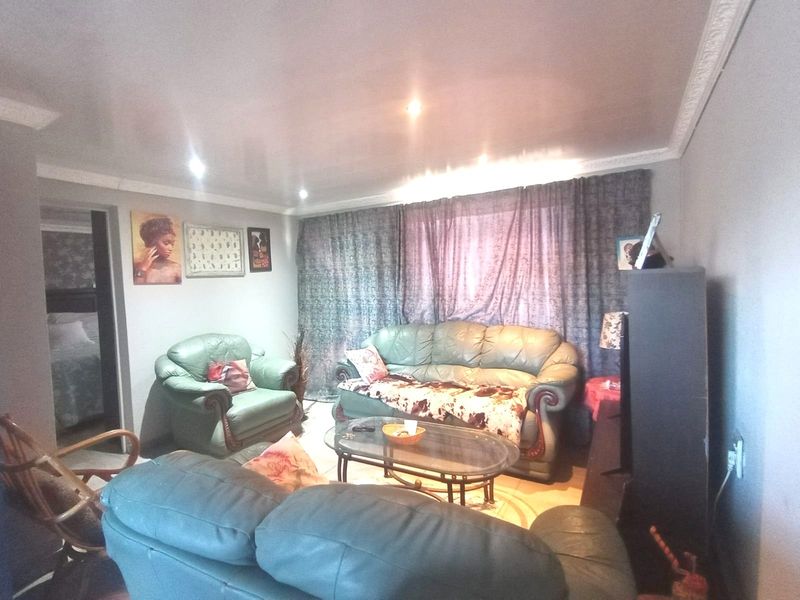 A living room featuring recessed downlighting and decorative ceiling cornicing, providing a functional space with potential for modern updates.