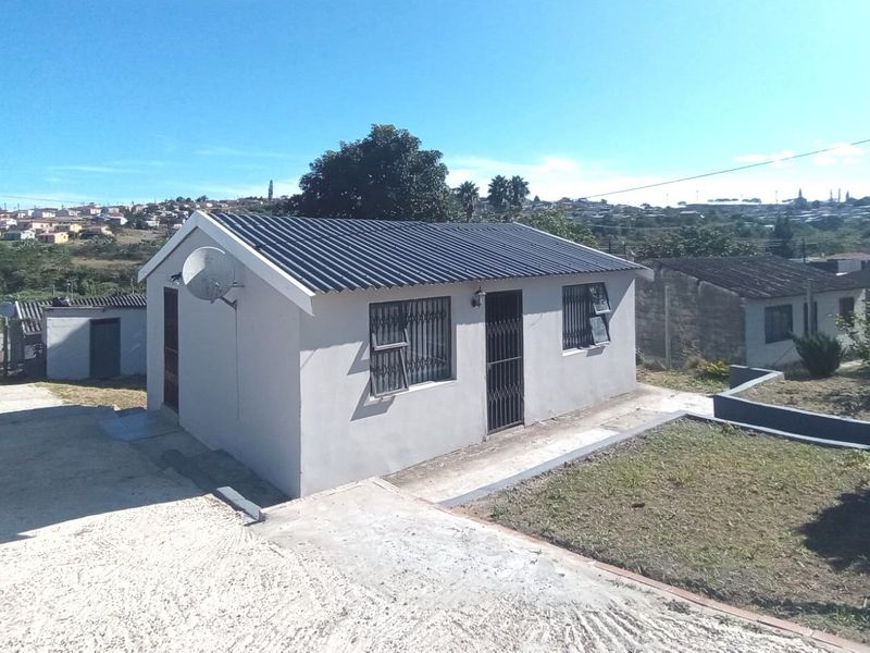 A detached single-story house featuring a corrugated metal roof, security gates, and a concrete driveway in a residential setting.