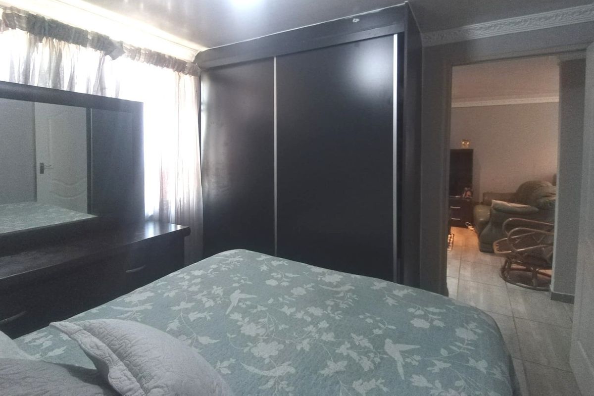 A bedroom featuring a built-in wardrobe and decorative crown molding, with an adjacent view into the living area.