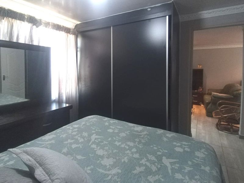 A bedroom featuring a built-in wardrobe and decorative crown molding, with an adjacent view into the living area.