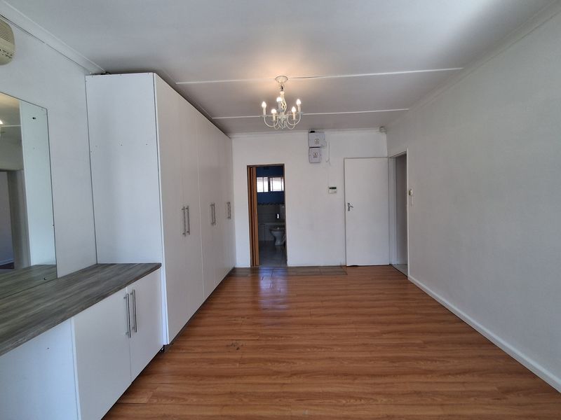 Spacious bedroom featuring extensive built-in cupboards, laminate flooring, and direct access to an en-suite bathroom.