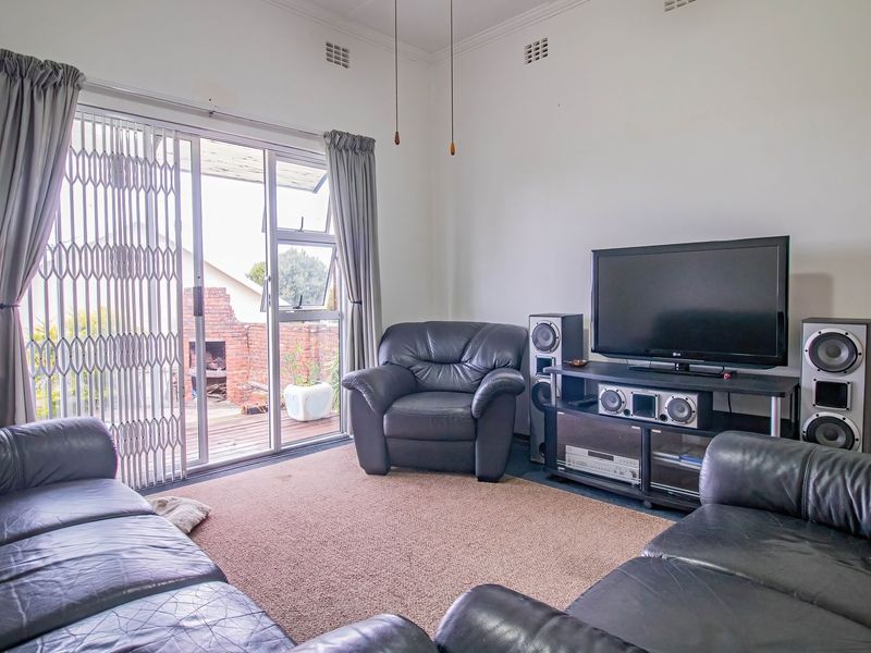 A comfortable living room featuring a sliding glass door with security gate, providing access to an outdoor patio area.