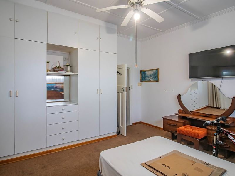 A bedroom featuring extensive white built-in cabinetry, a ceiling fan, and carpeted flooring.