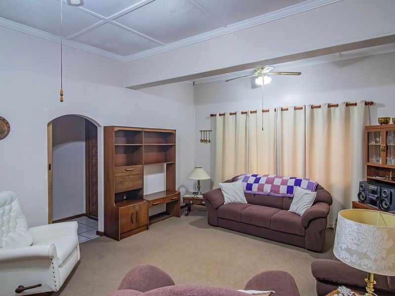 A spacious living room featuring a coved ceiling, a central ceiling fan, and a distinctive arched doorway leading to an adjacent area.