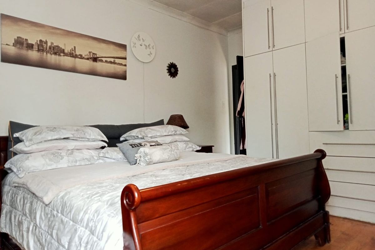 A bedroom featuring wooden flooring and white built-in cupboards providing ample storage space.