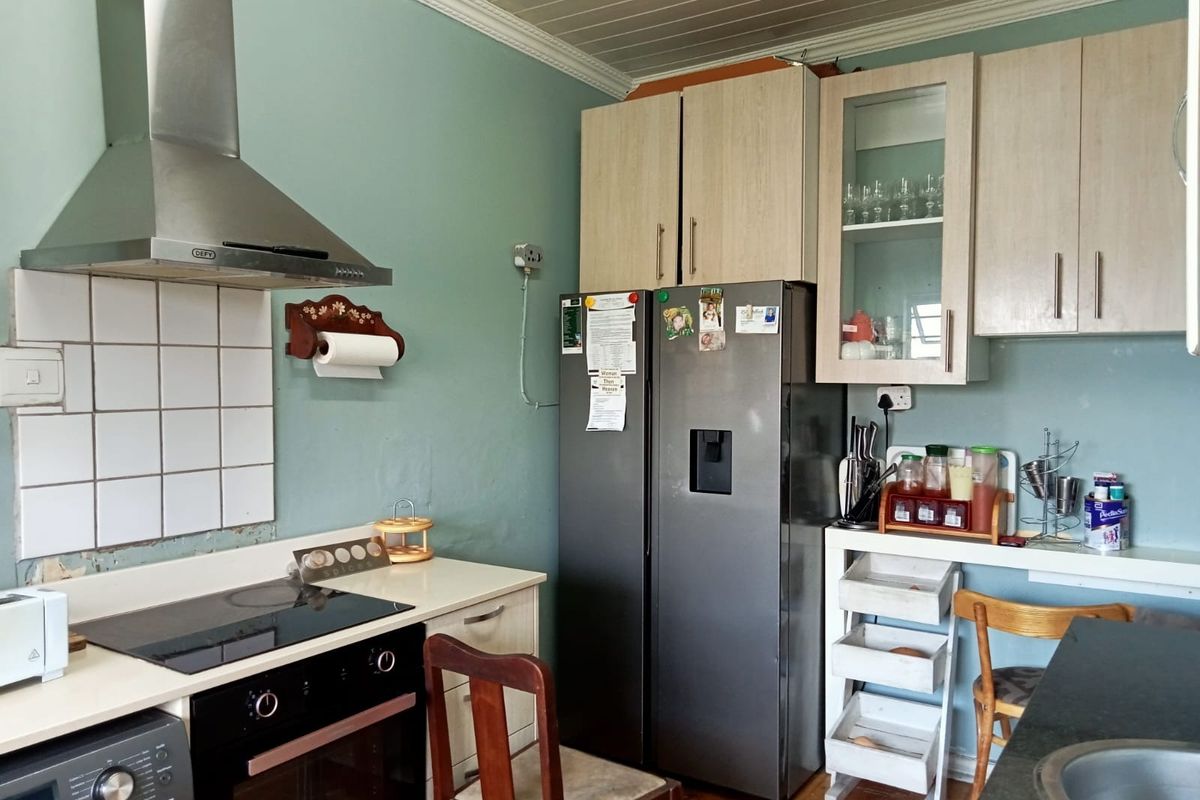 A functional kitchen featuring built-in cabinetry, an electric hob, oven, and stainless steel extractor fan, with some minor wall finish repairs required.