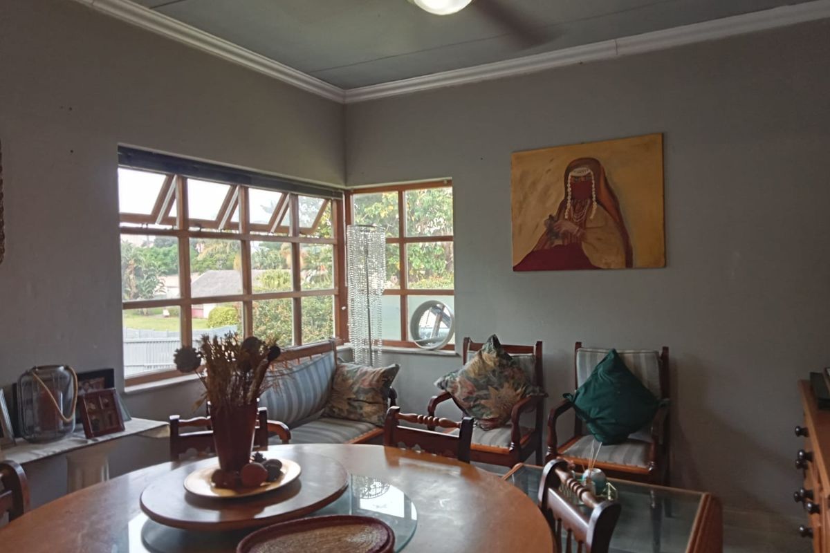 A living room featuring timber-framed windows, ceiling fan, and classic cornicing, offering a comfortable space with natural light.