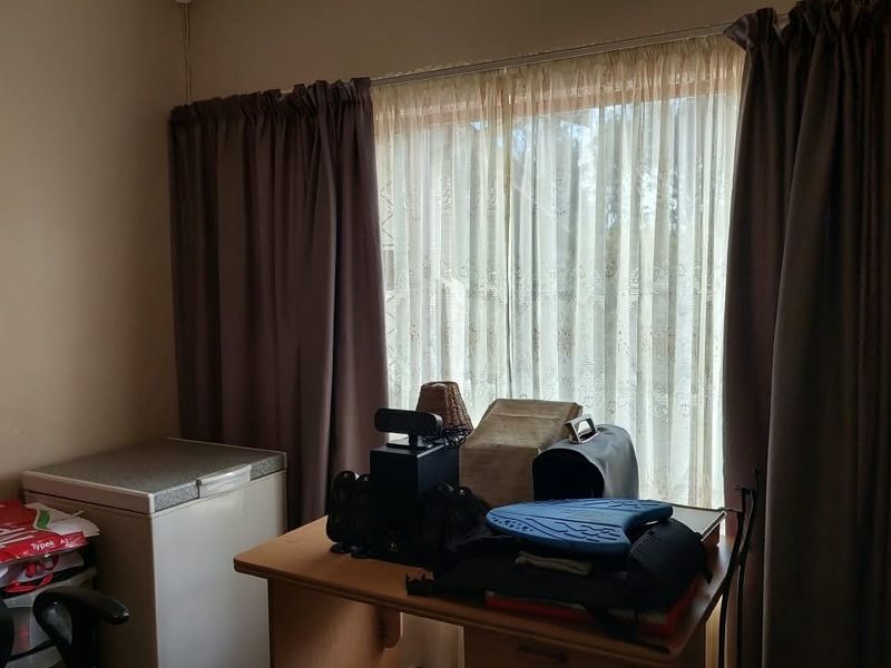 A bedroom featuring a large window with installed curtain tracks and curtains, providing natural light to the space.