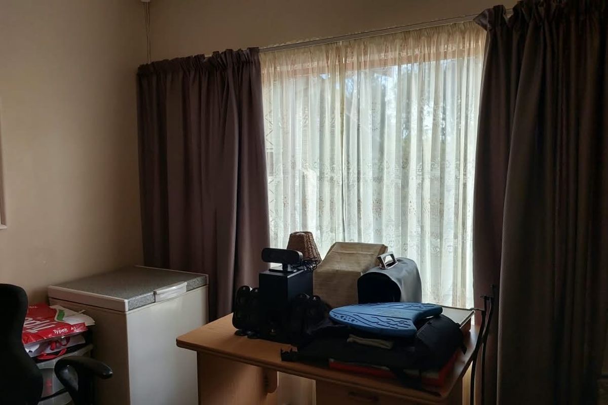 A bedroom featuring a large window with installed curtain tracks and curtains, providing natural light to the space.