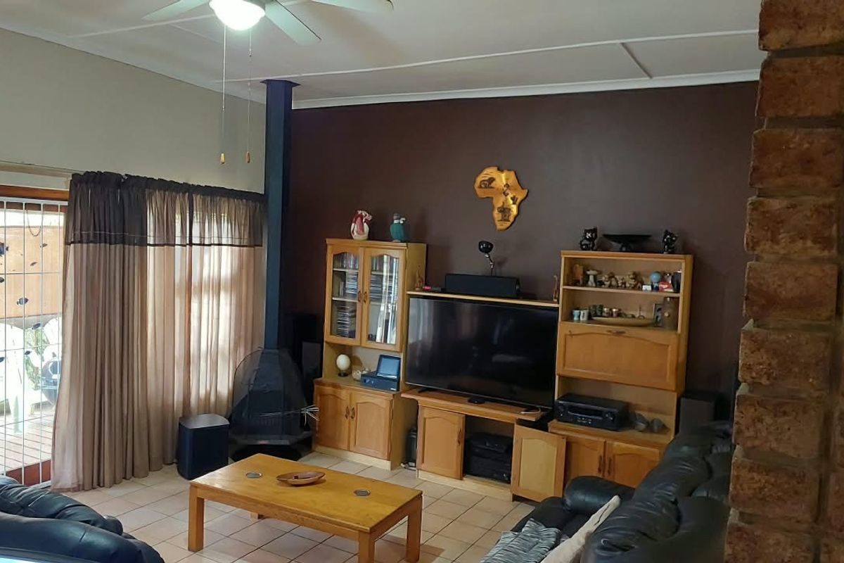 Spacious living room featuring an exposed brick wall, tiled flooring, a freestanding fireplace, and direct access to the outdoor area through sliding glass doors.