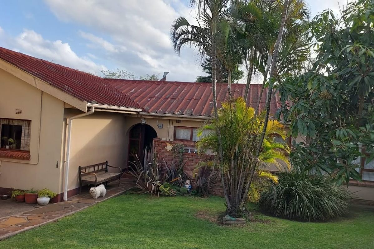 Rear view of the house featuring a tiled roof, brick accents, and a paved walkway leading to an arched entrance.