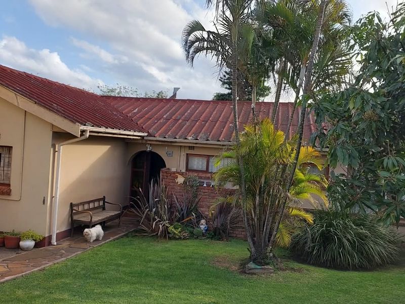 Rear view of the house featuring a tiled roof, brick accents, and a paved walkway leading to an arched entrance.