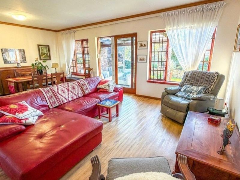 Spacious open-plan living and dining area featuring laminate flooring, large timber-framed windows, and direct access to the outdoor patio area.