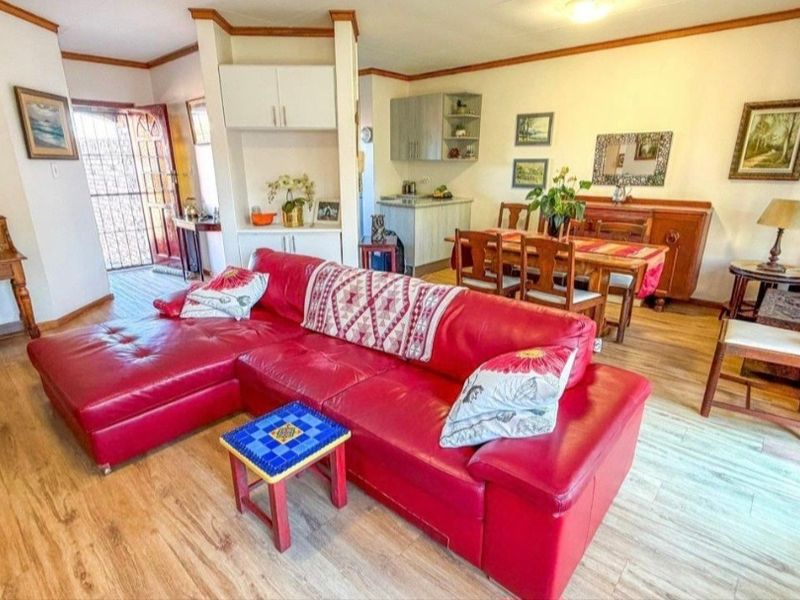 Open-plan living and dining area featuring laminate flooring, built-in cabinetry, and direct access to the exterior through a security gate.