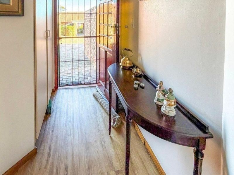 Entrance hallway featuring laminate flooring, built-in storage cupboards, and a secure exterior door leading to the outdoor area.