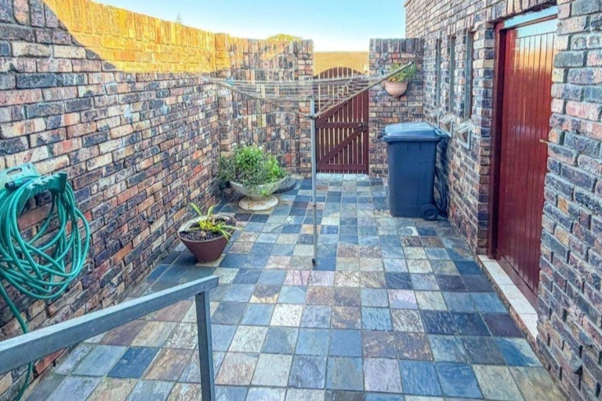 A private rear courtyard featuring face brick walls, slate tile paving, and a secure timber gate access.