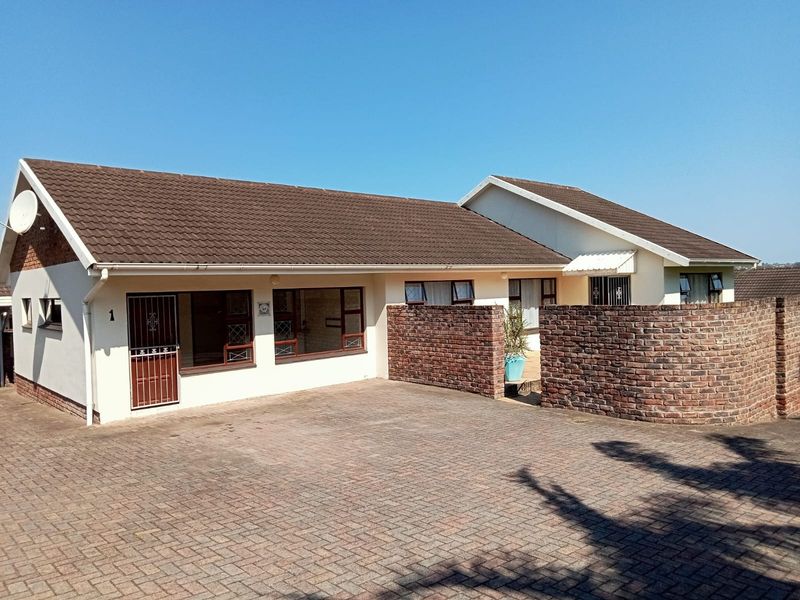 Front elevation of a cluster home featuring a paved driveway, facebrick boundary wall, and tiled roof.
