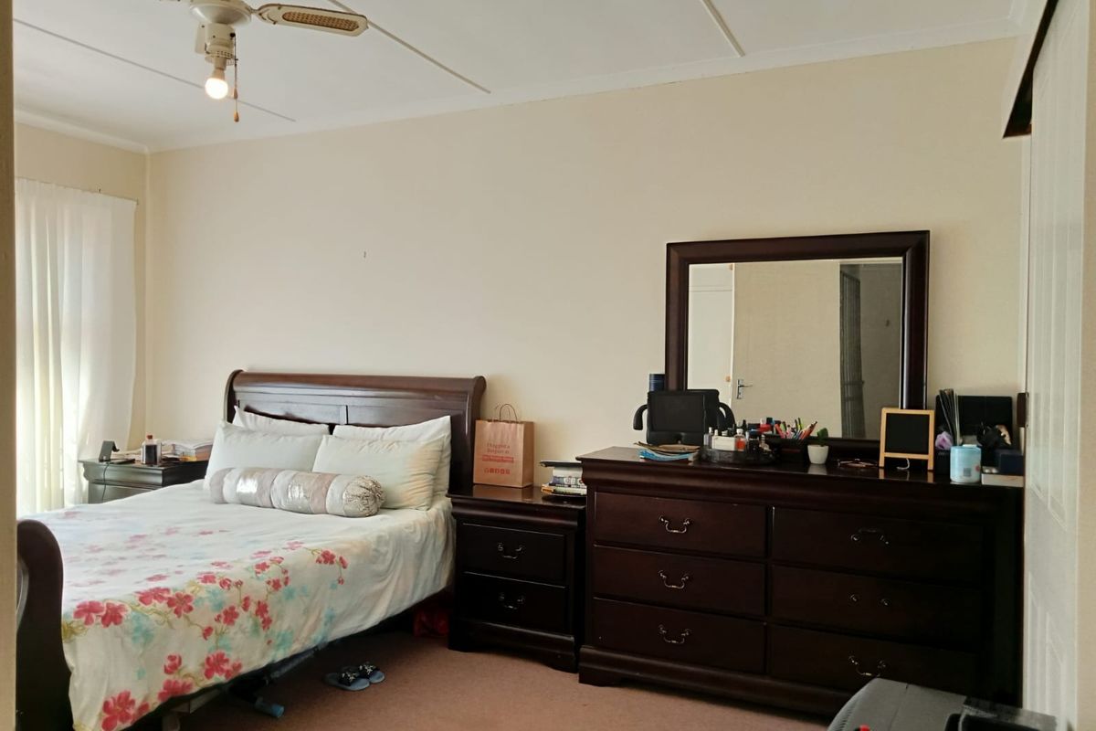 A standard bedroom featuring a ceiling fan and built-in cupboard space, offering a functional layout with neutral wall finishes.