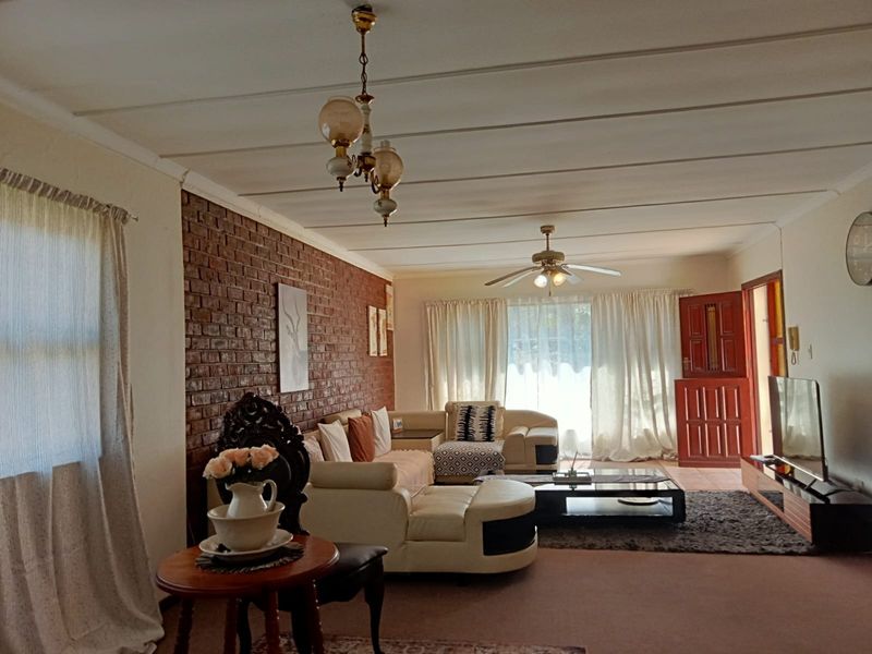 Spacious living room featuring an exposed brick accent wall, ceiling fan, and direct access to the exterior via a stable door.
