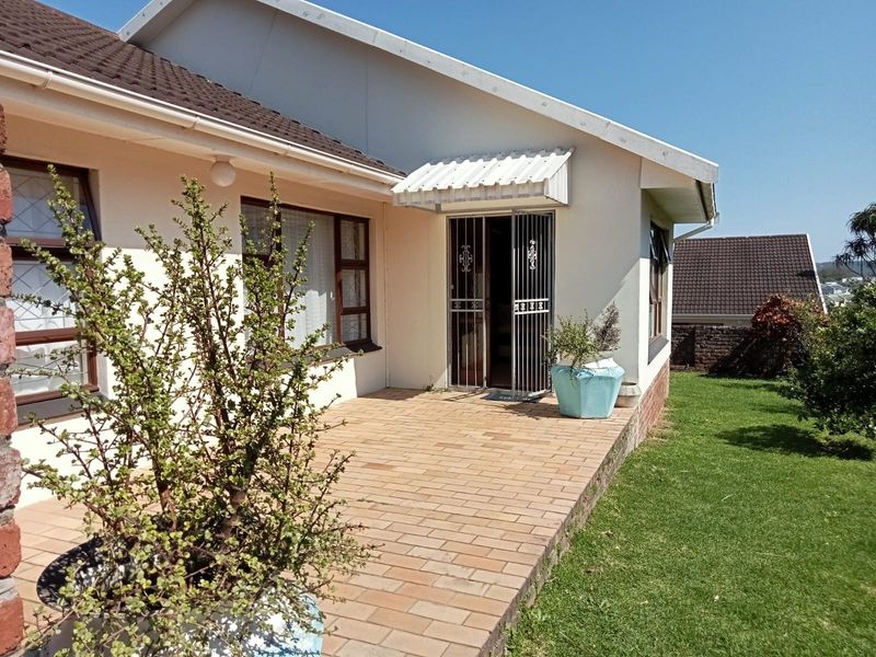 A well-maintained rear exterior view featuring a brick-paved patio, a secure entrance with a metal gate, and a neat garden area.
