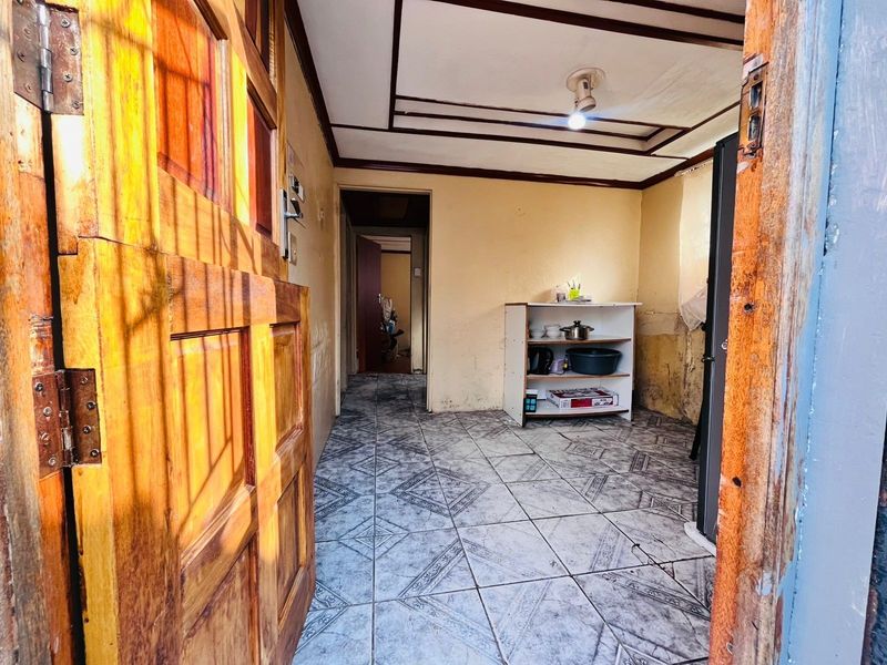 An entry area featuring tiled flooring and a timber door, showing signs of wear and requiring cosmetic updates to the wall surfaces.