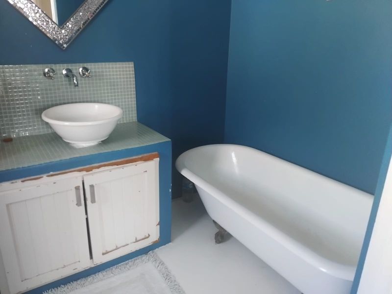 A bathroom featuring a classic clawfoot-style bathtub, a vessel sink set on a tiled vanity, and bold blue wall finishes.