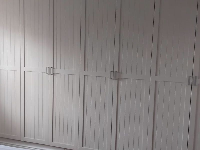 A bedroom featuring floor-to-ceiling built-in wardrobes with white panelled doors and modern hardware.