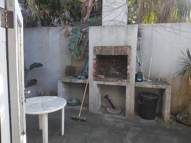 Outdoor patio area featuring a built-in brick braai and concrete prep surfaces, requiring maintenance and cosmetic updates to improve the entertainment space.