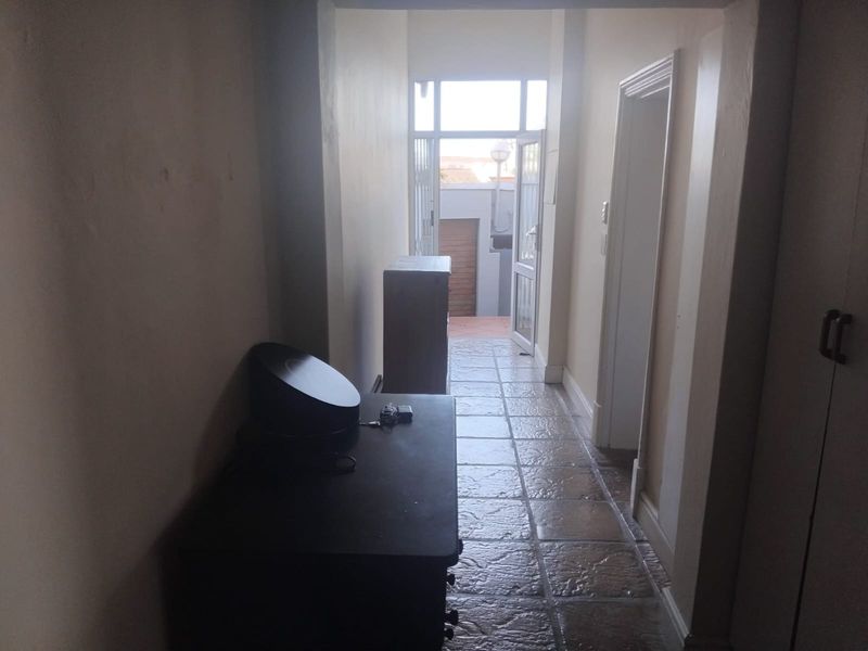 A tiled hallway leading to an exterior doorway, featuring built-in storage cupboards and neutral wall finishes.