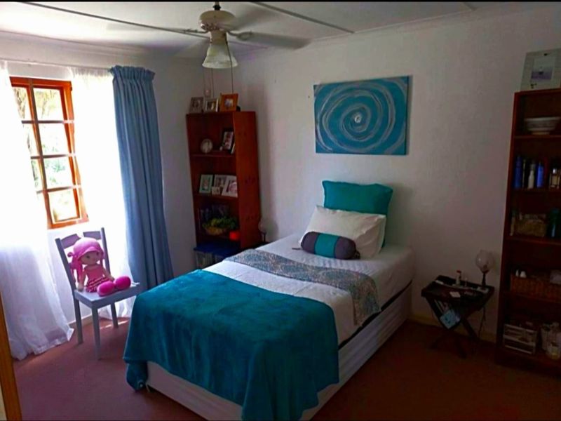 A standard bedroom featuring carpeted flooring, a ceiling fan, and a timber-framed window, providing a functional and lived-in space.
