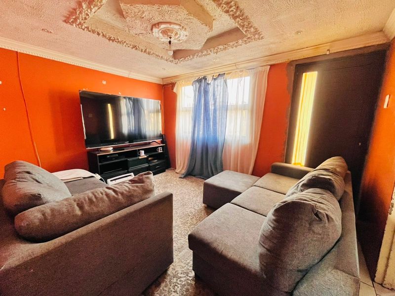 Living room featuring an ornate ceiling rose, decorative cornice, and recessed lighting, currently requiring wall surface repairs and cosmetic updates.