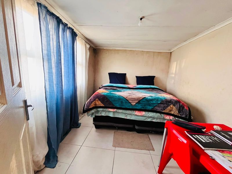 A bedroom featuring tiled flooring and neutral walls, currently requiring cosmetic updates to the wall and ceiling finishes to improve its overall condition.