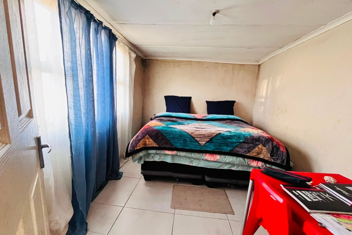 A bedroom featuring tiled flooring and neutral walls, currently requiring cosmetic updates to the wall and ceiling finishes to improve its overall condition.
