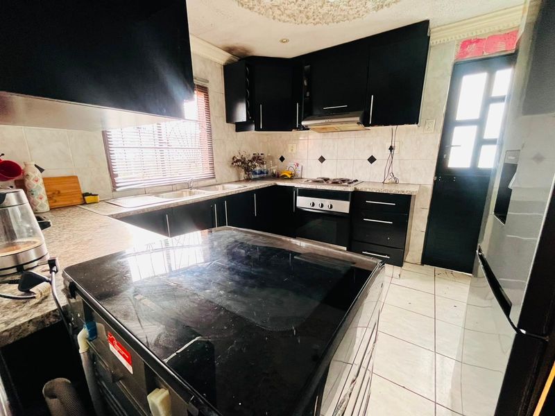 A kitchen featuring black cabinetry, granite countertops, and built-in appliances. The space includes tiled flooring and backsplash, with visible signs of wear and smoke damage.