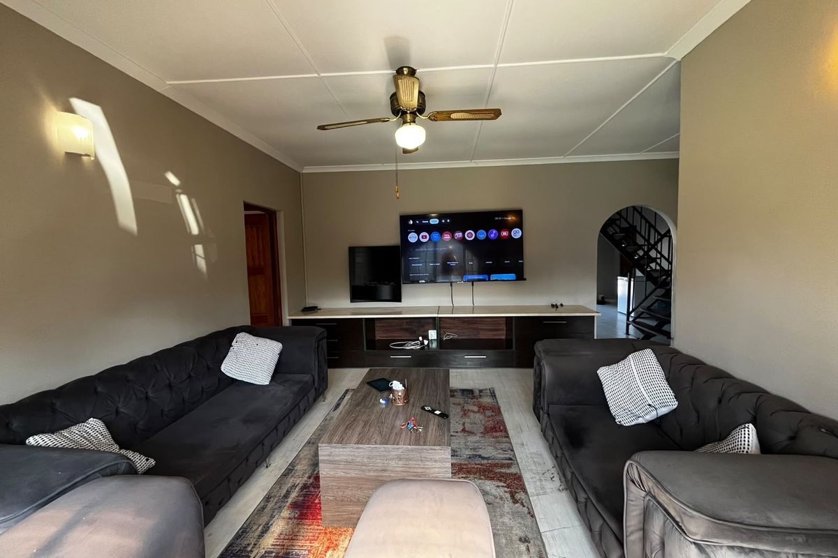 A comfortable living room featuring a built-in media console, ceiling fan, and an open archway leading to a staircase.