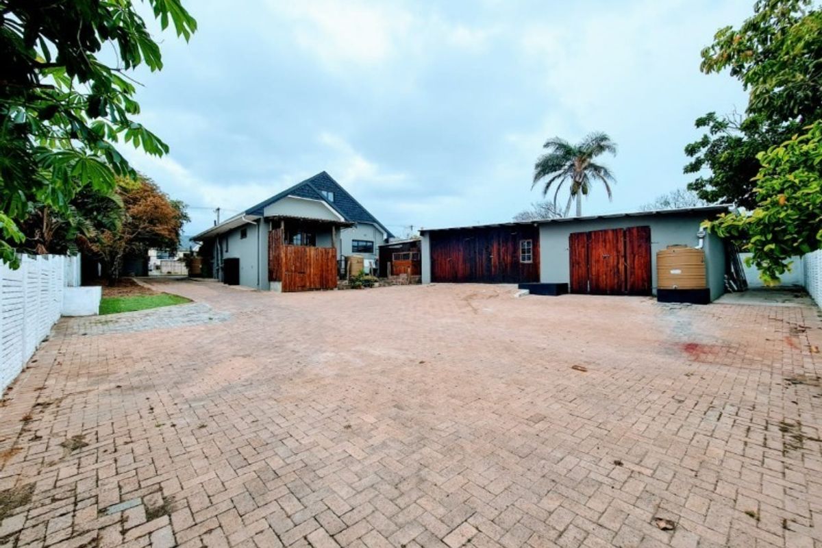 Spacious paved rear courtyard area featuring a garage with timber doors and a water storage tank, providing ample parking and utility space.