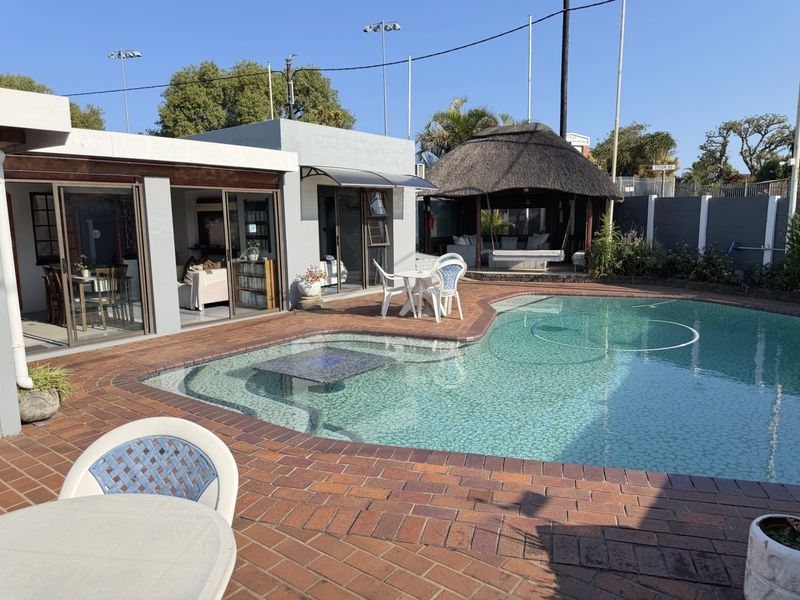 Outdoor pool area featuring brick paving, a swimming pool, and a thatched lapa, providing a functional space for outdoor entertainment and relaxation.