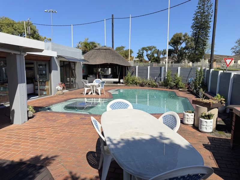 Outdoor entertainment area featuring a swimming pool, brick-paved patio, and a thatched gazebo, perfect for relaxation and hosting guests.
