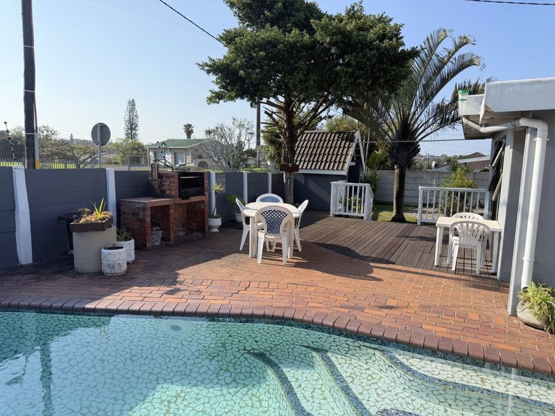 Outdoor entertainment area featuring a swimming pool, brick paved patio, timber decking, and a built-in brick braai facility.