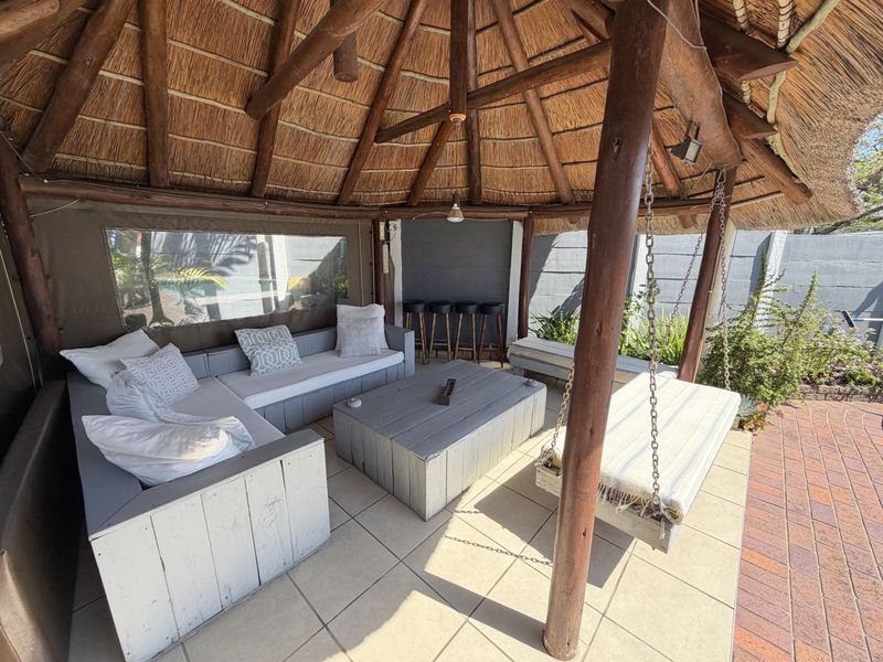 Covered outdoor patio area featuring a traditional thatched roof, timber support structure, tiled flooring, and a built-in bar counter.